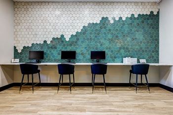Three chairs are placed in front of a desk with a laptop on it.